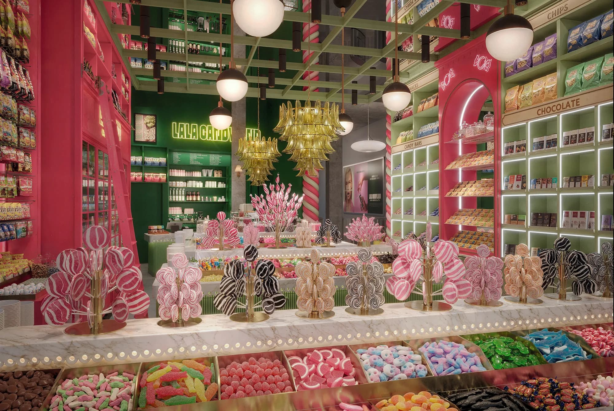 A long marble counter lined with brass lollipop trees of pink, white and black swirl lollipops above bins of loose candy, with lit chocolate cubbies to the right.